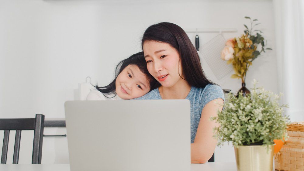 Asian working mothers on the computer with her child leaning on her